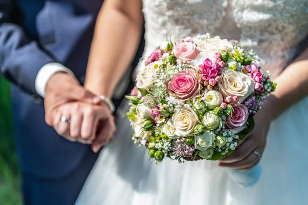 Mãos noivo e noiva com anéis de casamento e flores do buquê de casamento celebração símbolo do amor — Fotografia de Stock