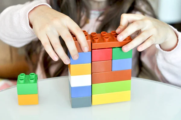 Child playing with plastic colorful blocks constructor at kindergarten. Close up of little girl hands building with colorful construction at home. Little girl with educational toys blocks at preschool — Stock Photo, Image