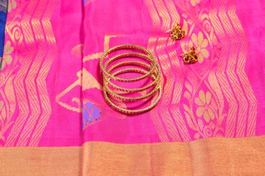 Bilezikleri ve küpeleri olan Hint pembesi ipek sarisi.