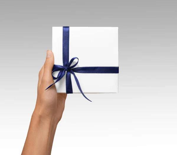 İzole kadın tatil hediyesi beyaz kutusuyla mavi kurdele beyaz arka plan üzerinde tutan eller — Stok fotoğraf