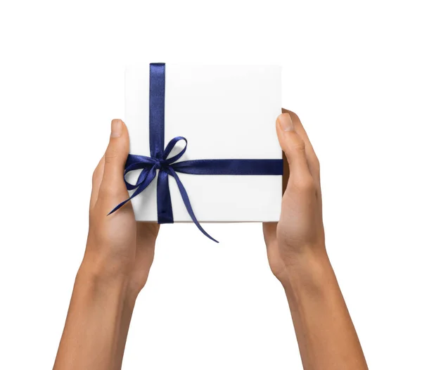 Las manos aisladas de la mujer que sostienen la caja blanca del regalo de vacaciones con la cinta azul sobre un fondo blanco —  Fotos de Stock