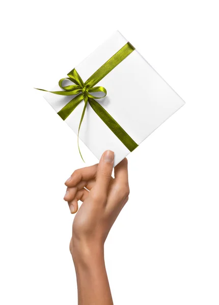 Las manos aisladas de la mujer que sostienen la caja blanca del regalo de vacaciones con la cinta verde en un fondo blanco — Foto de Stock