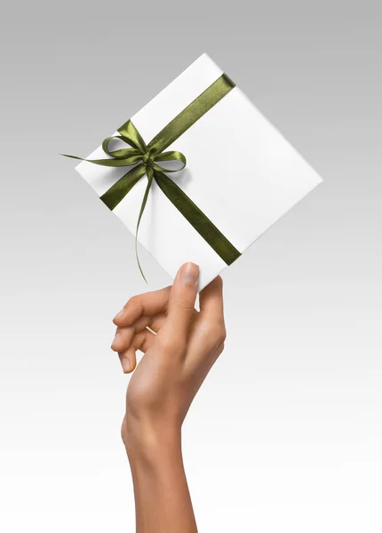 Las manos aisladas de la mujer que sostienen la caja blanca del regalo de vacaciones con la cinta verde en un fondo blanco —  Fotos de Stock