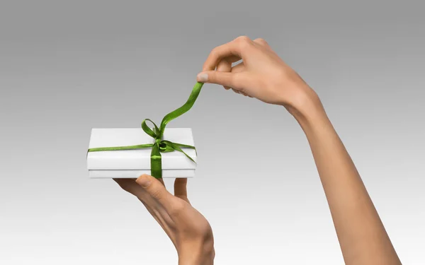 Isolato donna mani in possesso di vacanza regalo scatola bianca con nastro verde su uno sfondo bianco — Foto Stock