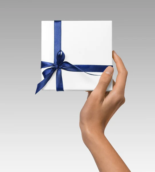 Mulher mão segurando feriado presente caixa branca com fita azul — Fotografia de Stock