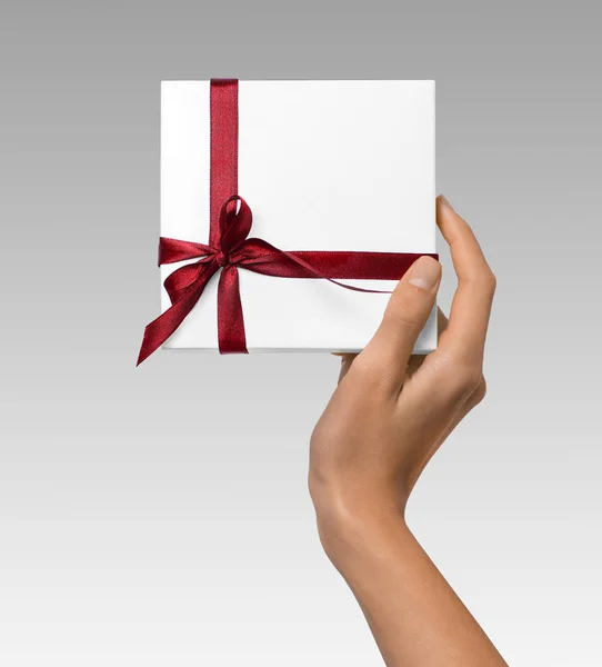 Mulher mão segurando feriado presente caixa branca com fita vermelha — Fotografia de Stock