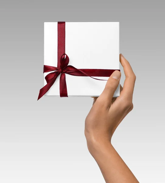 Mujer de mano celebración de vacaciones regalo caja blanca con cinta roja —  Fotos de Stock