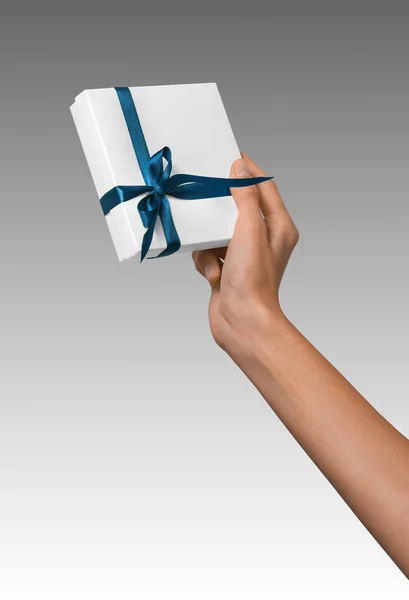 Kobieta ręka trzyma Holiday Present Box biały z niebieską wstążką — Zdjęcie stockowe