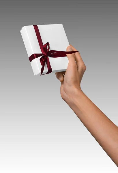 休日存在の白い箱に赤いリボンを持つ女性の手 — ストック写真