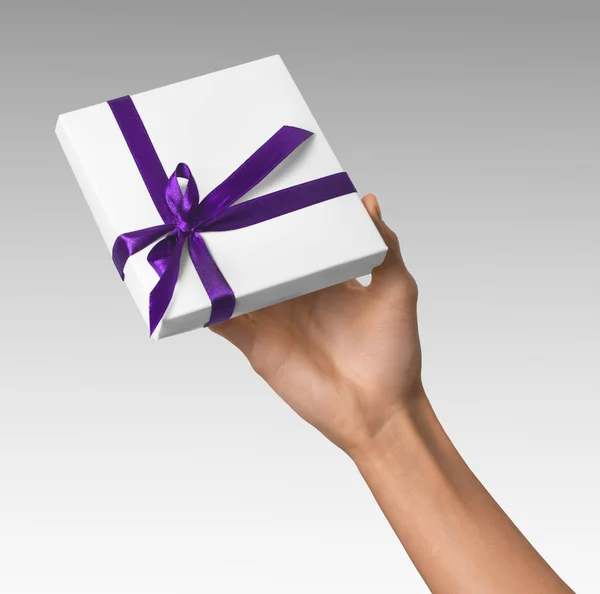 Donna mano tenuta vacanza regalo scatola bianca con nastro viola — Foto Stock