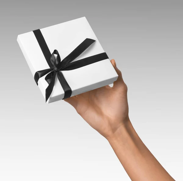 Mujer mano celebración día de fiesta regalo blanco caja con cinta negra oscura — Foto de Stock
