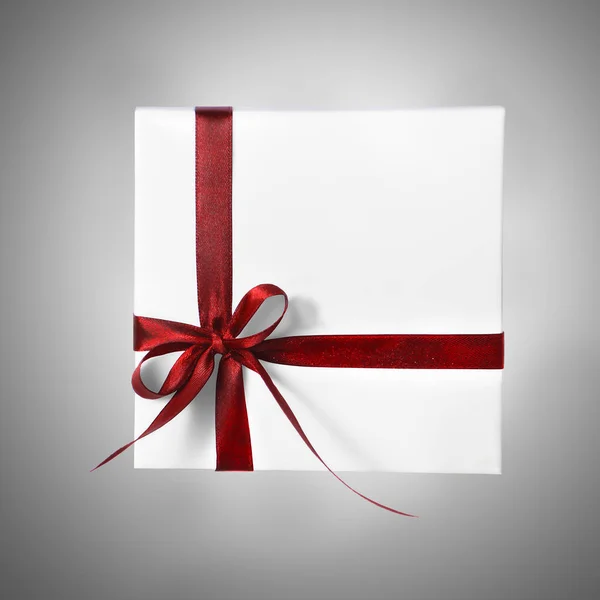 Isolado Holiday Presente caixa branca com fita vermelha em um fundo gradiente Fotografia De Stock