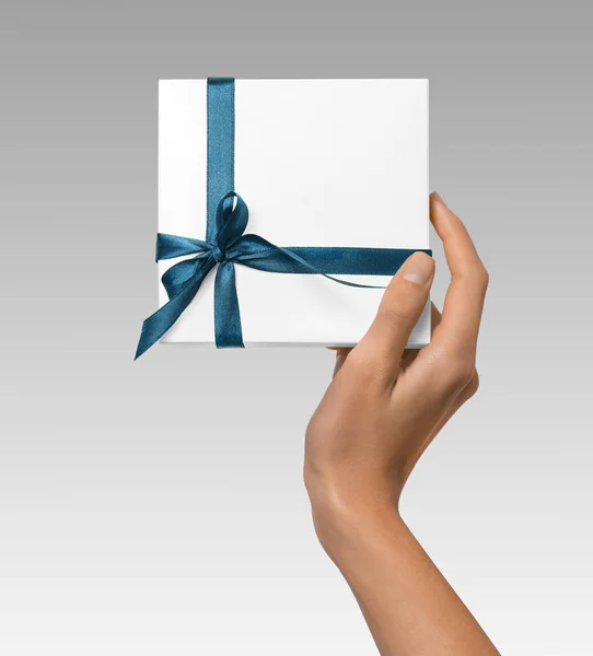 Femme main tenant vacances cadeau boîte blanche avec ruban bleu Photos De Stock Libres De Droits
