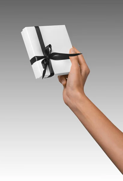 Mujer mano celebración día de fiesta regalo blanco caja con cinta negra oscura Imagen De Stock
