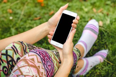 şık, trendy kadın ellerinde çiçeklerle yeşil çim zemin üzerine beyaz cep telefonunuzu bir egzersiz molası sırasında kapatın