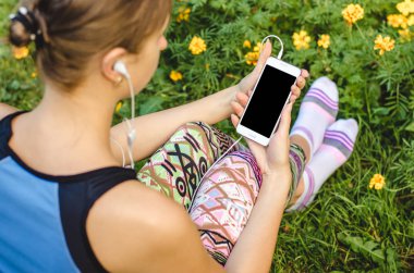 şık, trendy kadın ellerinde çiçeklerle yeşil çim zemin üzerine beyaz cep telefonunuzu bir egzersiz molası sırasında kapatın