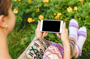 şık, trendy kadın ellerinde çiçeklerle yeşil çim zemin üzerine beyaz cep telefonunuzu bir egzersiz molası sırasında kapatın