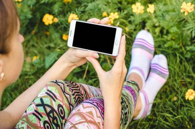 şık, trendy kadın ellerinde çiçeklerle yeşil çim zemin üzerine beyaz cep telefonunuzu bir egzersiz molası sırasında kapatın