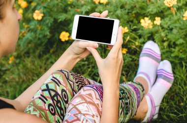 şık, trendy kadın ellerinde çiçeklerle yeşil çim zemin üzerine beyaz cep telefonunuzu bir egzersiz molası sırasında kapatın