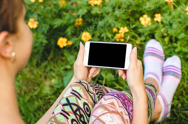 şık, trendy kadın ellerinde çiçeklerle yeşil çim zemin üzerine beyaz cep telefonunuzu bir egzersiz molası sırasında kapatın