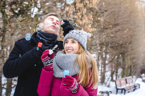 Romantische paar verliefd blazen van zeepbellen, samen plezier in winter kleding buiten. Soep bubbels. — Stockfoto