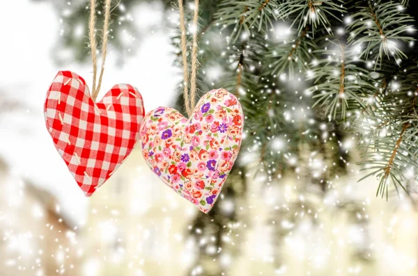 Heart made by hand hanging on a green Christmas tree drawing snowfall toned. Valentines day. Hand embroidered decoration. — Stock Photo, Image