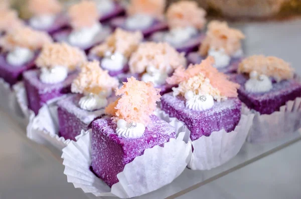 Delicious wedding reception sweets luxury purple color desserts with edible pearl and edible crystal stones on top on glass plate. Candy bar desser.
