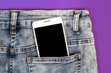 Close Up Bussines Fashion Stylish Smart Phone Screen Copy Space White Mobile in Black Jeans Back Pocket Denim on ultra violet trend color background