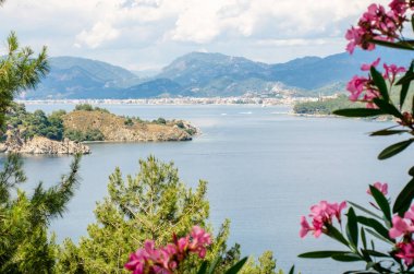 Sahilde deniz ve yat ve gemi çerçevede yüksek dağlar yaz panoraması.