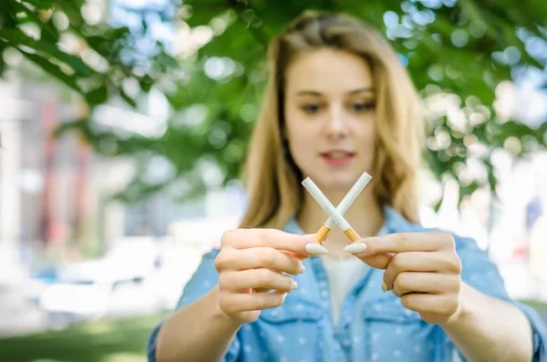 Close Up Of Stylish Smiling Woman Smoking Cigarette Outdoor Denim Shirt in park on Nature Background Habit Prohibited Advertising