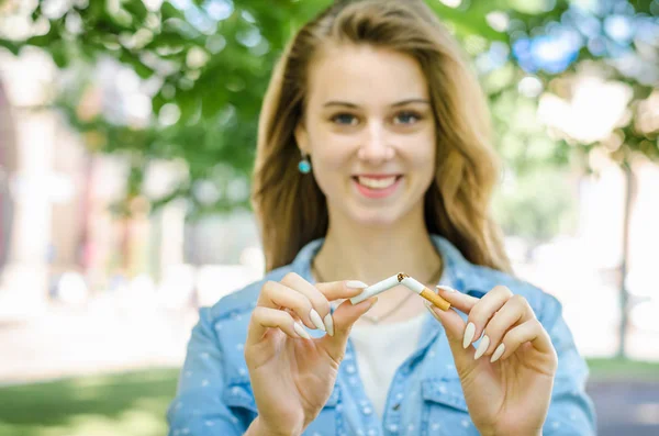 Close Up Of Stylish Smiling Woman Smoking Cigarette Outdoor Denim Shirt in park on Nature Background Habit Prohibited Advertising