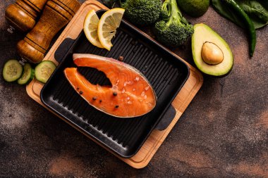 Tavada çiğ somon bifteği ve sağlıklı ürünler. Sağlıklı beslenme konsepti, yemek geçmişi. Üst görünüm.