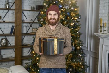 Yeni yıl arifesinde ev partisi adam Noel'de gülümseyen bağış hediye kırmızı şapkalı adam sakallı