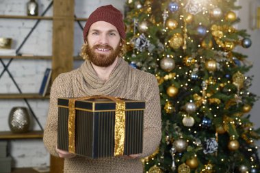 Noel hediyesi arka planda kameraya gülümseyen adam hediye hediye yılbaşı için hediye elleriyle dışarı adam ulaşır