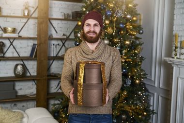Adam gülümsüyor ve Noel hediyeleri christmastree baxkground tatil ev kavramı kutularıyla tutar