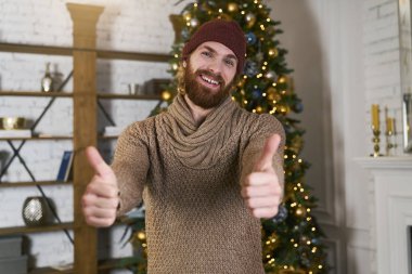 Noel ve yeni yıl kutlama gerçek duygular. Genç adam büyük jest Yaşasın dexorated arka plan üzerinde gösterilen sakallı. Noel ağacı.