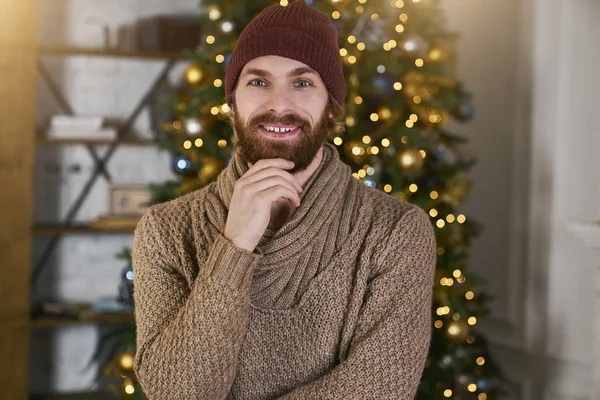 Moda sakallı genç hipsters düşünen ne onun kız arkadaşı veya arkadaş Noel ağacı arka plan üzerinde Noel ve yeni yıl için vermek. Xmas tasarımı ile rahat daireler. çatı partisi konsepti.