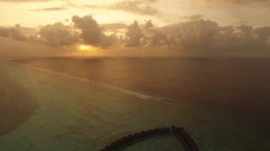 Lüks Tropikal resort Hint Okyanusu üzerinde günbatımında bungalovlar üzerinde uçan