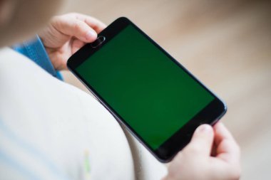 Çocuk bir telefon chroma keyer için yeşil bir ekran ile elinde tutuyor