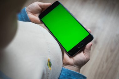Çocuk bir telefon chroma keyer için yeşil bir ekran ile elinde tutuyor