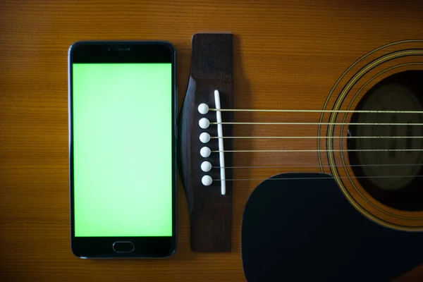 Smartphone with green screen on an acoustic guitar