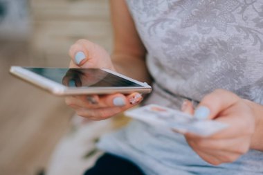 Kredi kartı tutan ve online alışveriş için cep telefonu kullanan bir kadın.. 