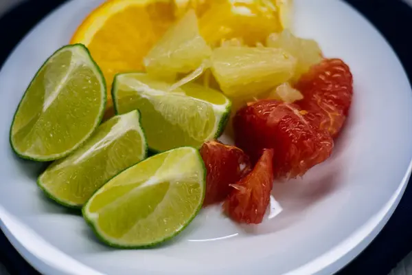 Стопка цитрусовых ломтиков. Апельсины и лимонные лаймы, грейпфруты, помело. на белой тарелке — стоковое фото