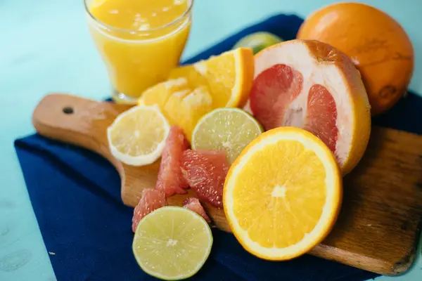 Цитрусові, апельсини, лимони, лимони, грейпфрут, помело на вінтажному дошці, лимонад та сік у склянці склянки на бірюзовому фоні — стокове фото