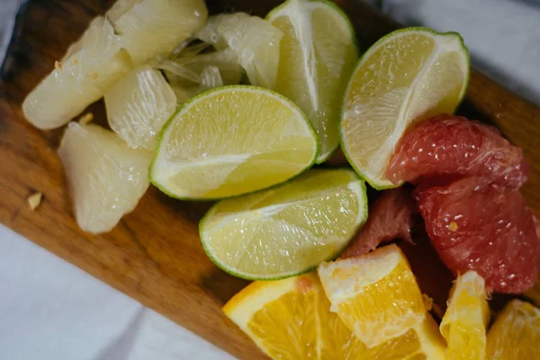 Pile de tranches d'agrumes. Oranges et citrons limes, pamplemousse, pomelo. Sur table en bois — Photo