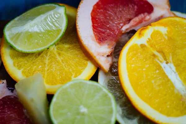 Various citrus fruit cut into slices orange, lemon, lime, grapefruit, pomelo. Spread out on a wooden board on a vintage background of natural wood texturing.