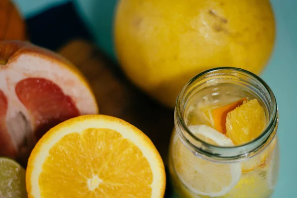 Цитрусові, апельсини, лимони, лимони, грейпфрут, помело на вінтажному дошці, лимонад та сік у склянці склянки на бірюзовому фоні — стокове фото
