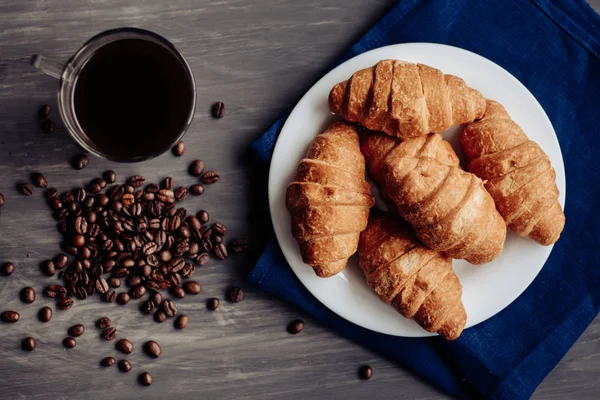Kaffeetasse und frisch gebackene Croissants auf Holzuntergrund. Ansicht von oben. — Stockfoto