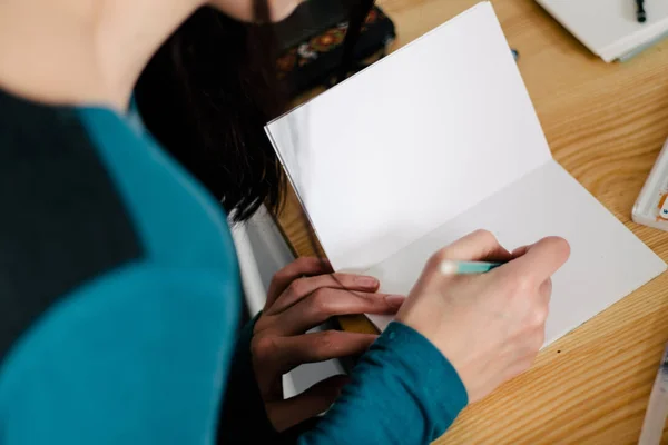 Primer plano de las manos femeninas tomando notas en el bloc de notas de la oficina — Foto de Stock