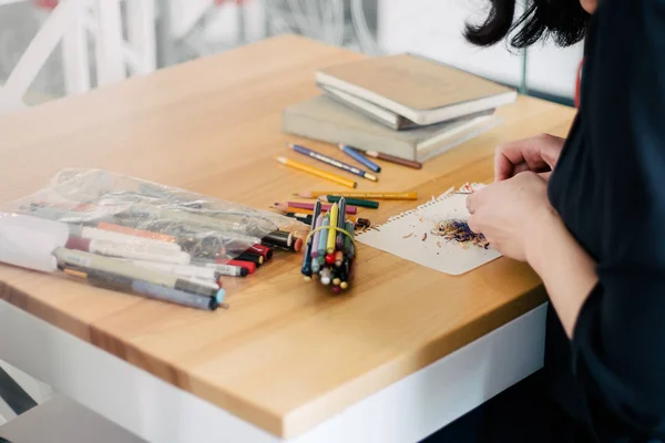 Gros plan des mains de la femme en utilisant taille-crayon vert beaucoup de crayons sur la table — Photo